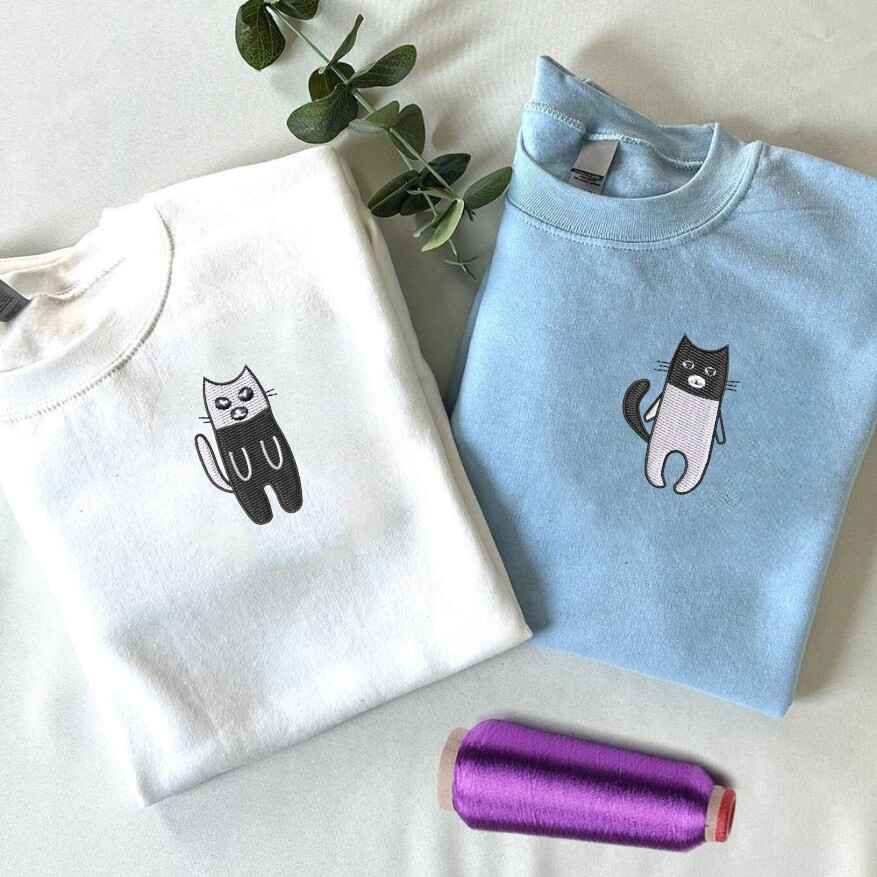 Matching couple sweatshirts with embroidered black and white cat designs
