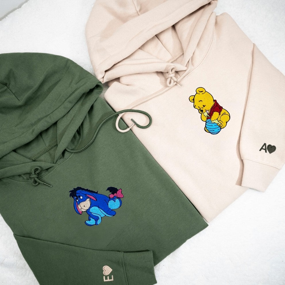 Green and beige hoodies with embroidered Eeyore and Winnie the Pooh characters.