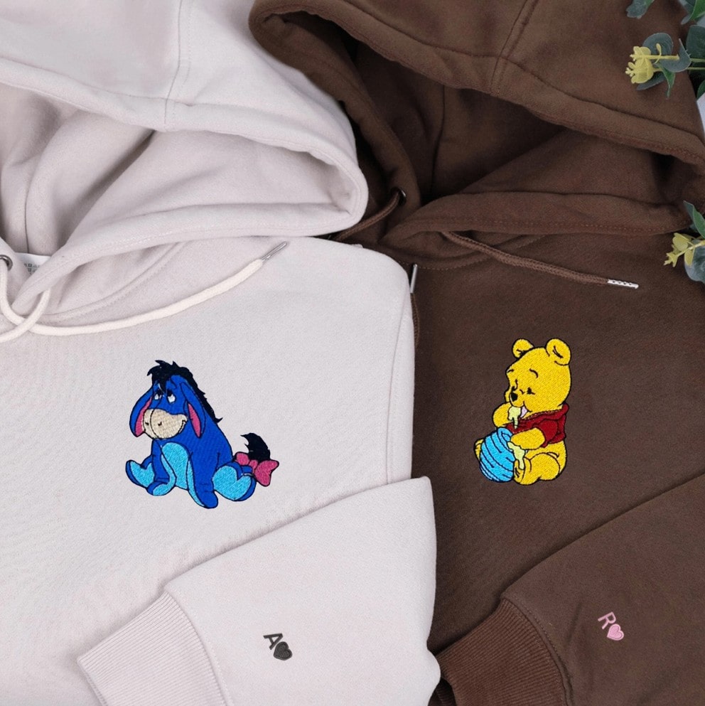 Neutral-tone hoodies with nostalgic embroidered characters and heart details.