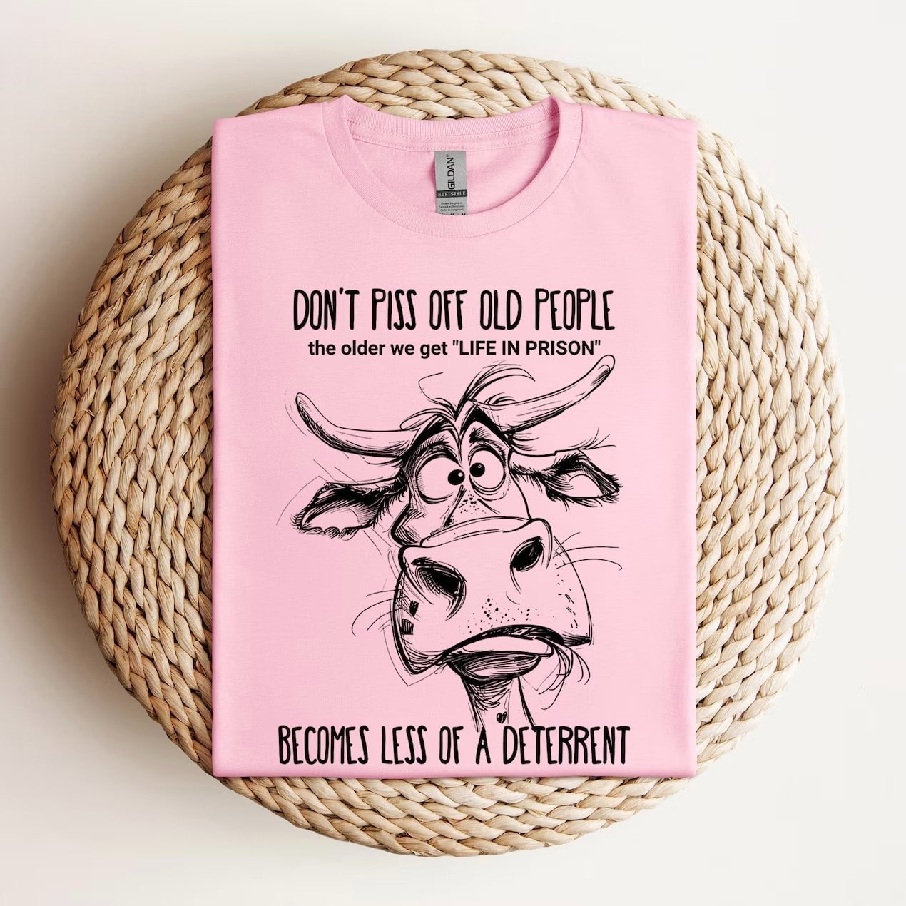 Pink tee with 'Don’t Piss Off Old People' cow graphic.