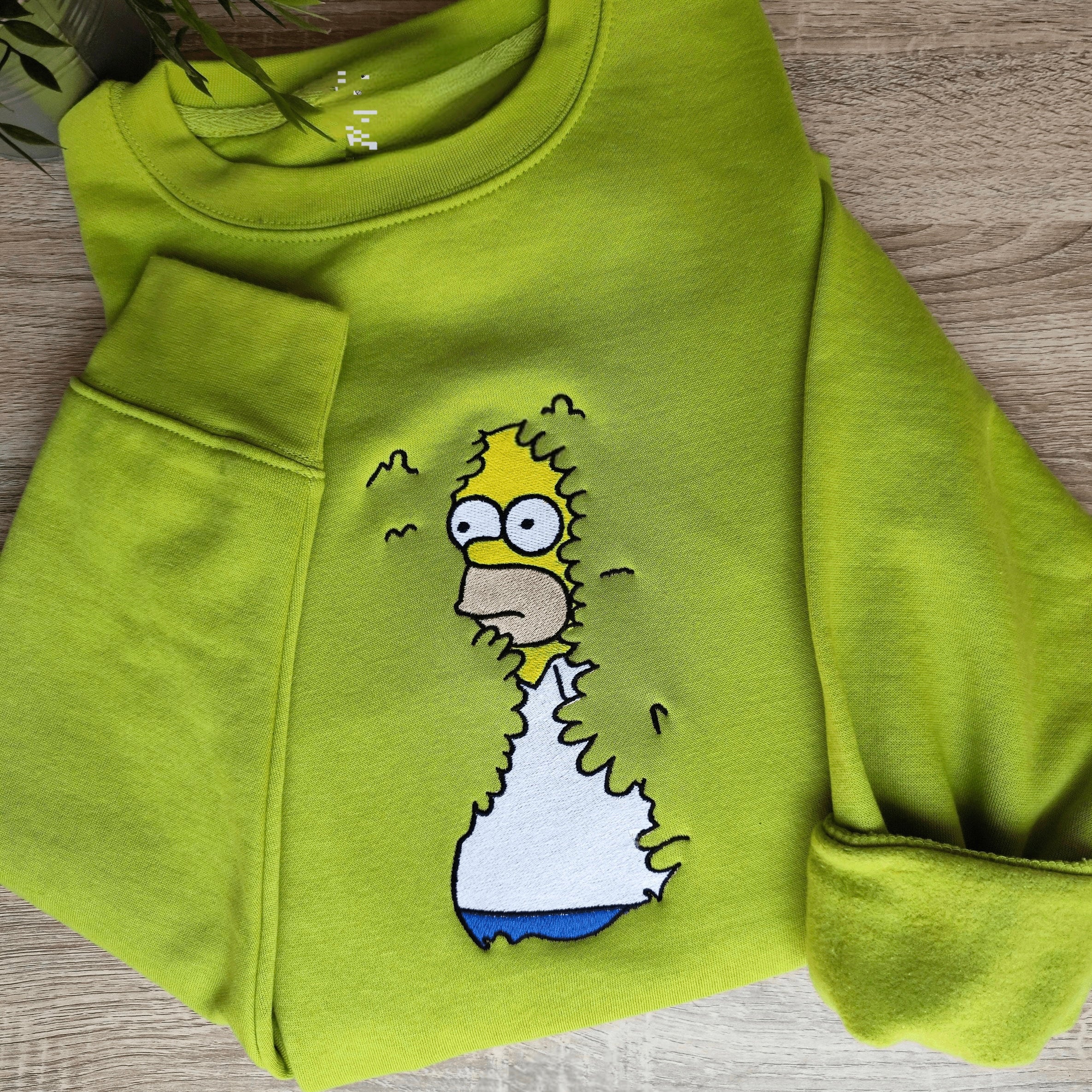 Meme shirts showcasing a funny green hoodie with an embroidered iconic cartoon moment, perfect for fans of funny meme t-shirts.
