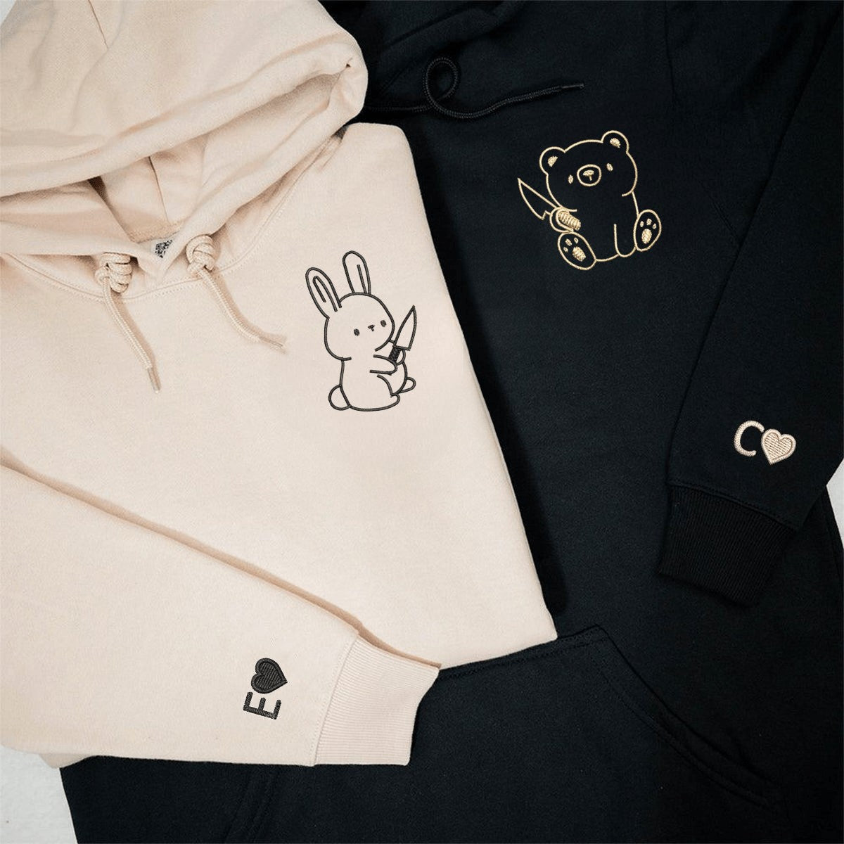 Couple hoodies with embroidered characters and personalized heart symbols on cuffs.