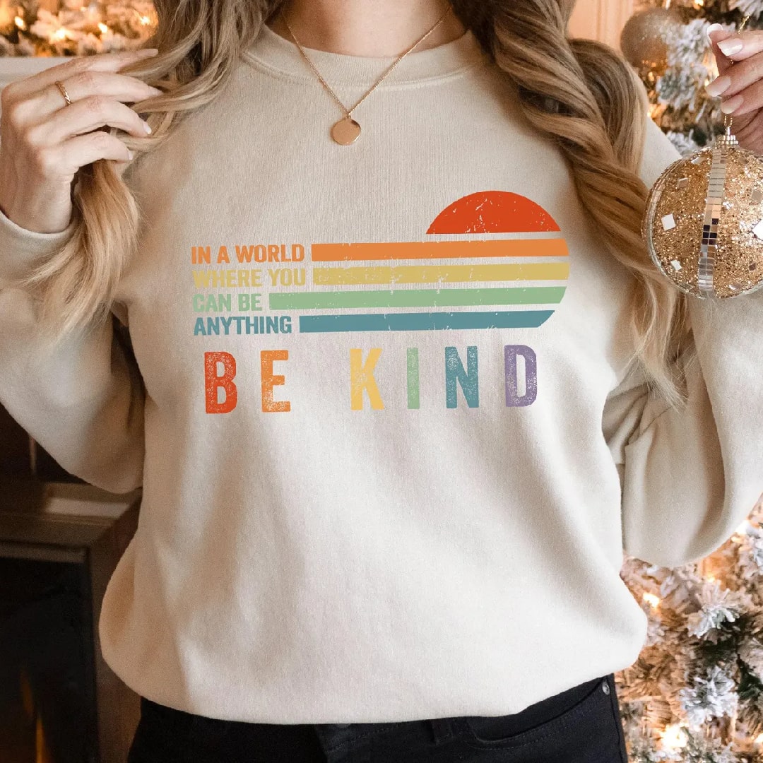 Light beige "Be Kind" sweatshirt featuring rainbow colors and sunset