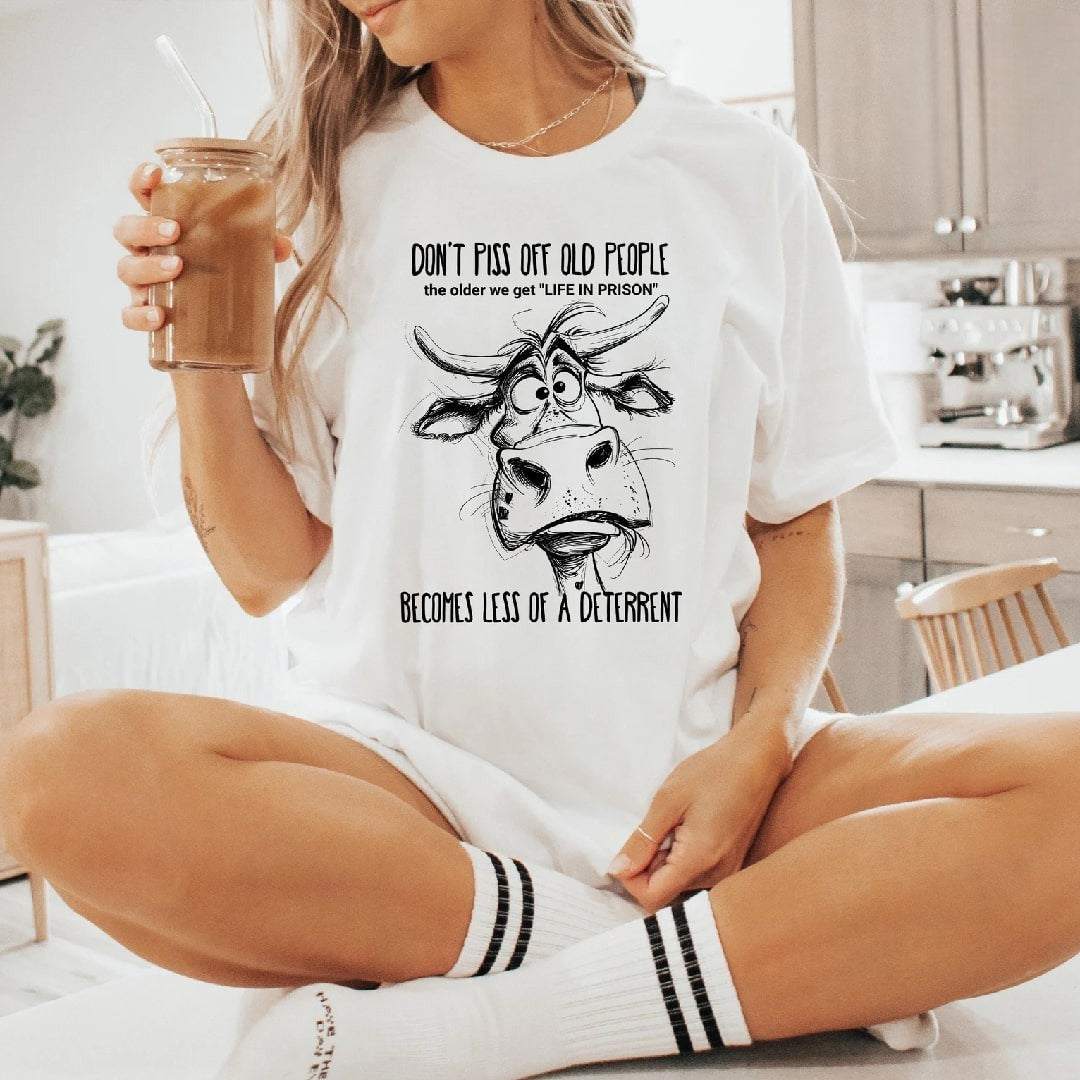 White "Don't Piss Off Old People" graphic tee with quirky cow design