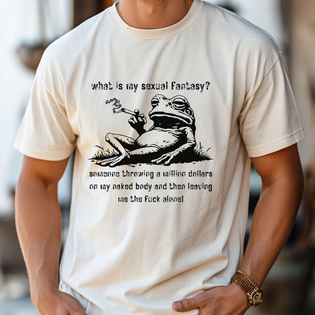 Graphic tee featuring a humorous frog design with the text 'What is my sexual fantasy?' and 'someone throwing a million dollars on my naked body and then leaving me the fuck alone'