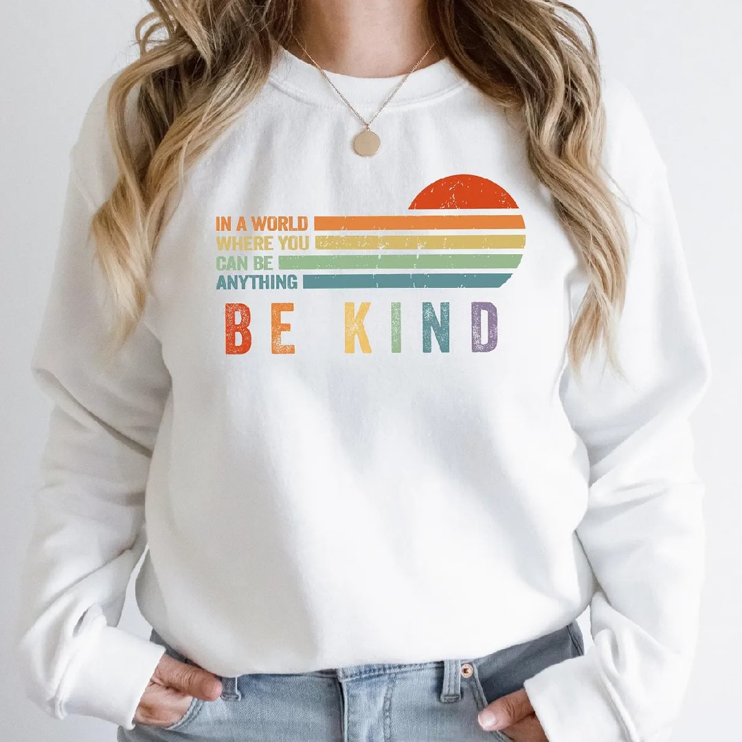 White "Be Kind" graphic sweatshirt with colorful rainbow sunset design