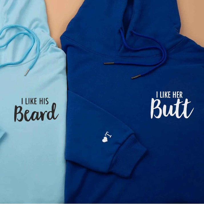 Playful beige and black couple hoodies with "I Like His Beard" and "I Like Her Butt" design, perfect gift for couples.
