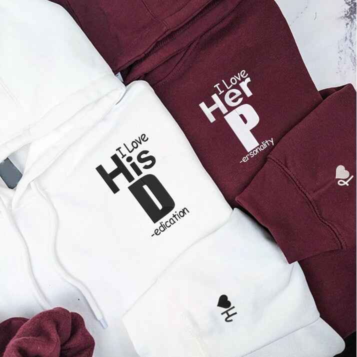 Matching couple hoodies in white and maroon with "I Love His Dedication" and "I Love Her Personality" text, unique and playful.
