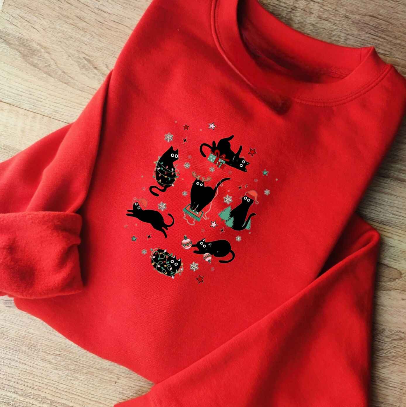 Holiday-themed sweatshirt featuring playful black cats and Christmas decorations
