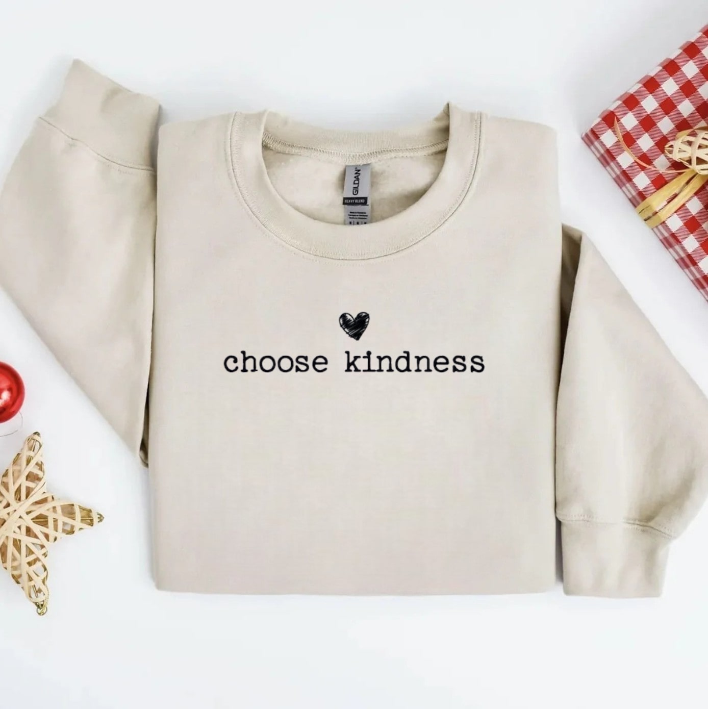 Close-up of pastel sand sweatshirt with embroidered kindness quote.