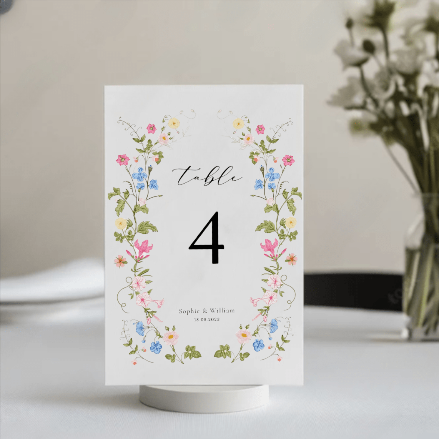 Elegant floral wedding table number with soft pastel flowers and bold text