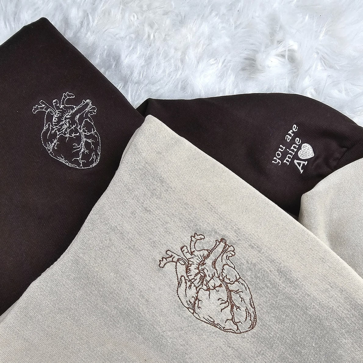 Soft cotton couple hoodies with intricate embroidered heart designs and personalized cuffs.