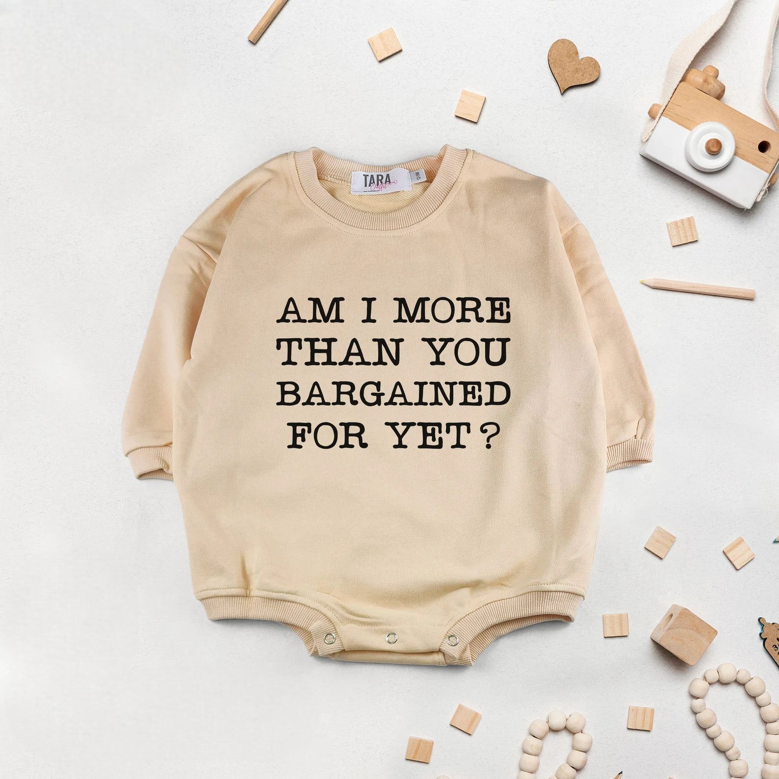 Close-up of sassy "Am I More Than You Bargained For?" baby onesie