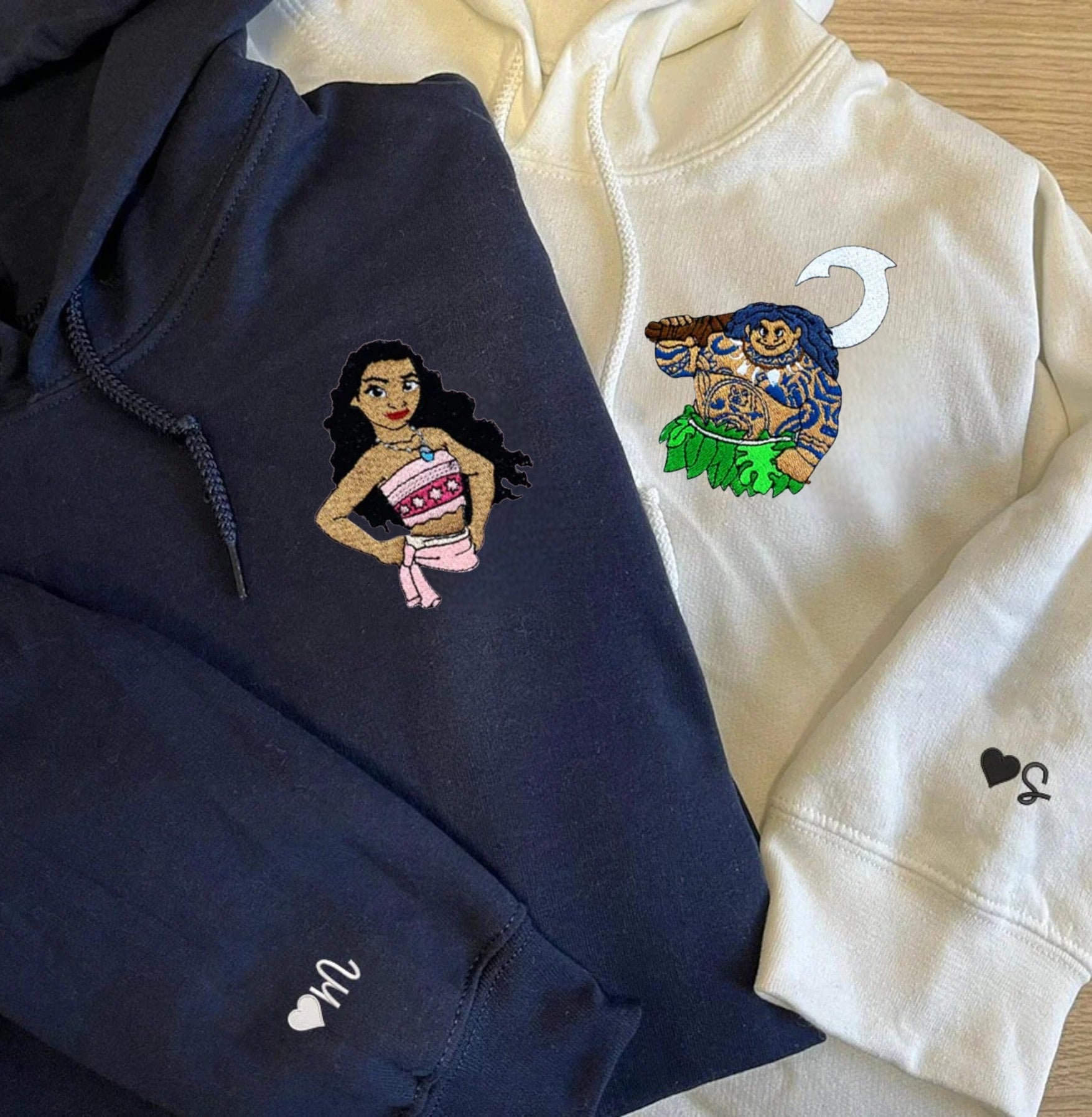 Matching navy and white couple hoodies with bold cartoon character embroidery.