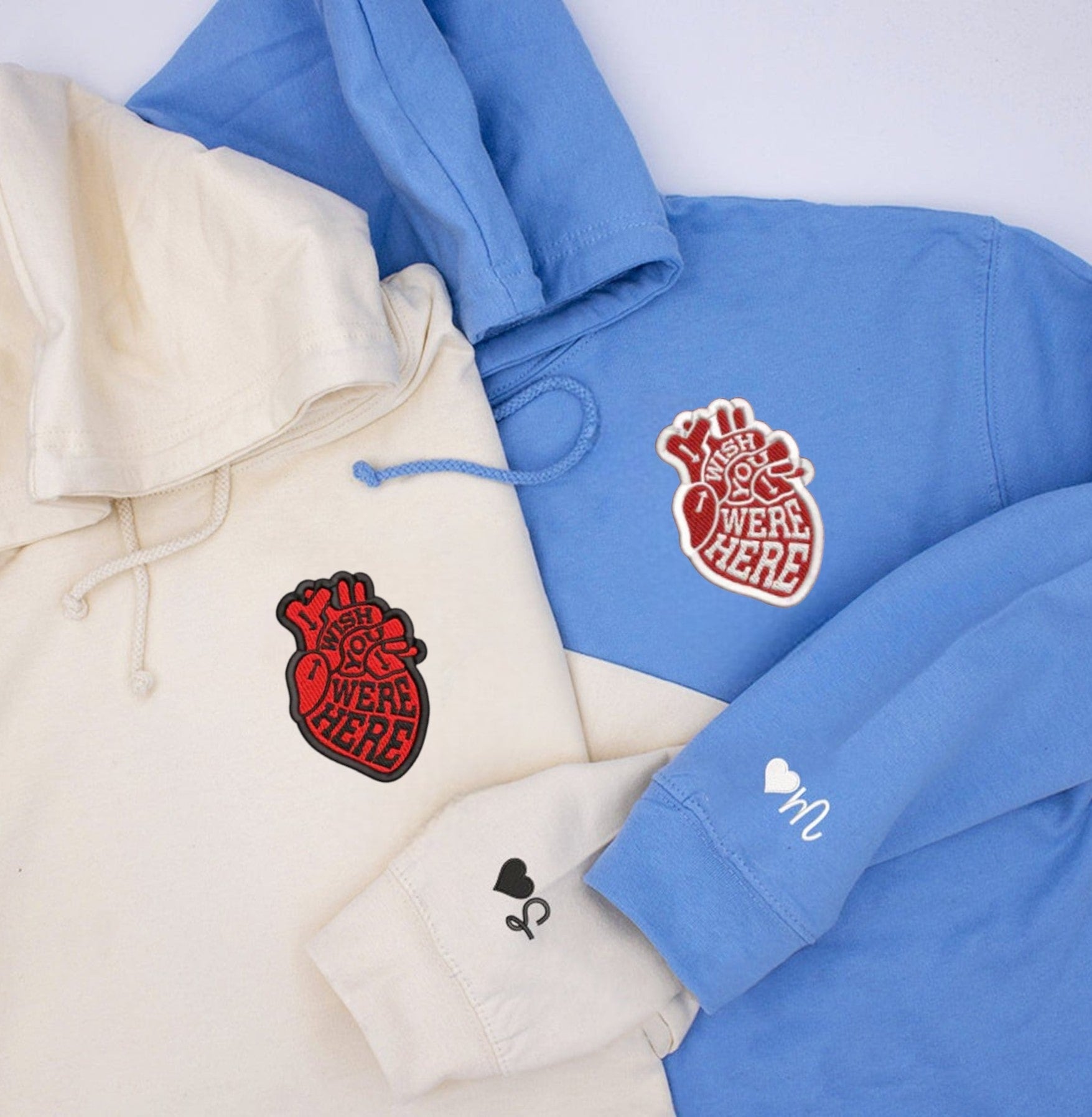 Sky blue and white sweatshirts with bold 'I Wish You Were Here' anatomical heart embroidery.