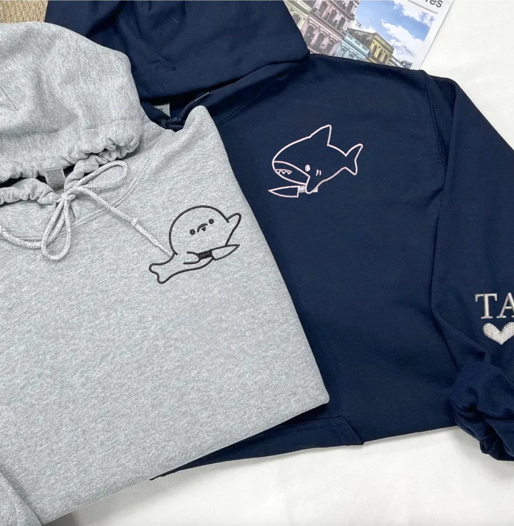 Green and beige sweatshirts for couples featuring quirky shark and seal embroidery.