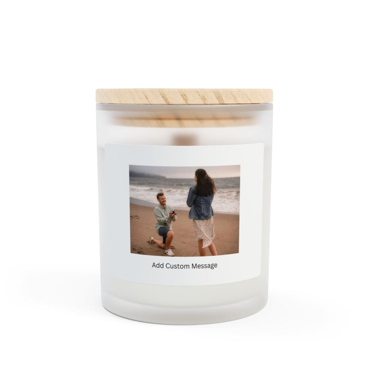 Clean and minimalist frosted glass candle with custom message label placed next to dried flowers on a table.
