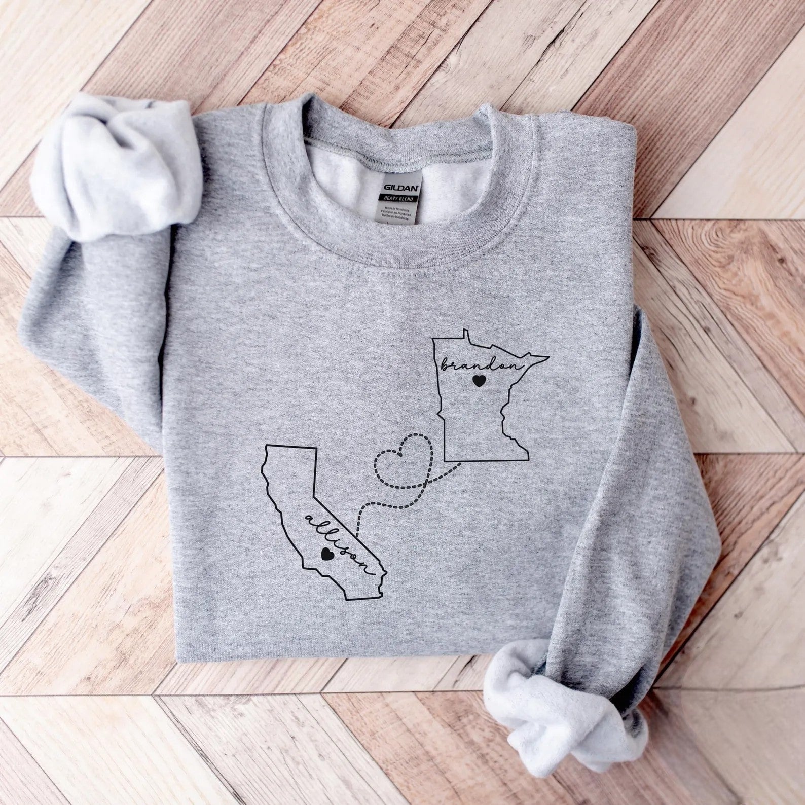 Custom long-distance relationship hoodie featuring two states and a connecting heart.