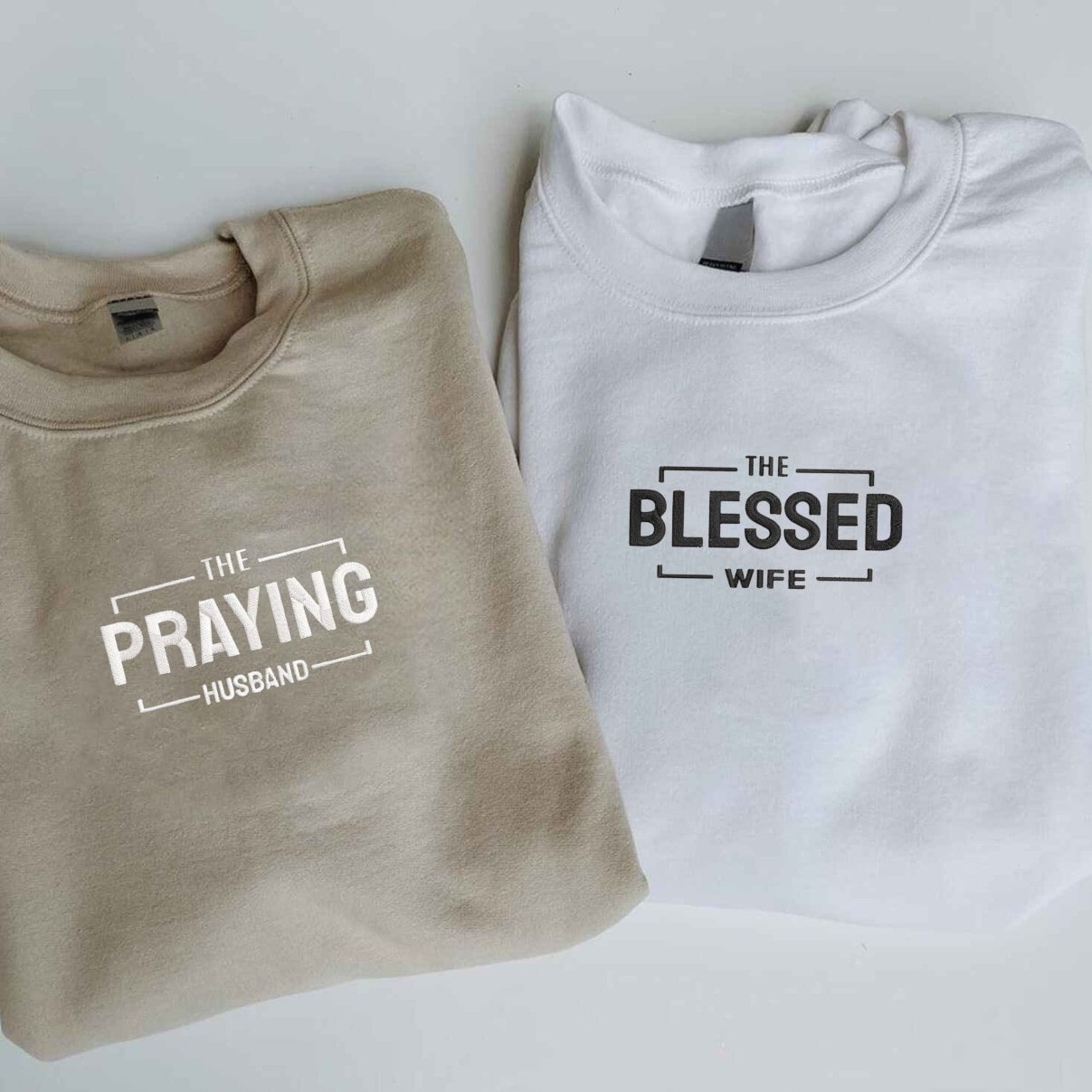 Matching couple hoodies in navy and brown with faith-inspired designs.
