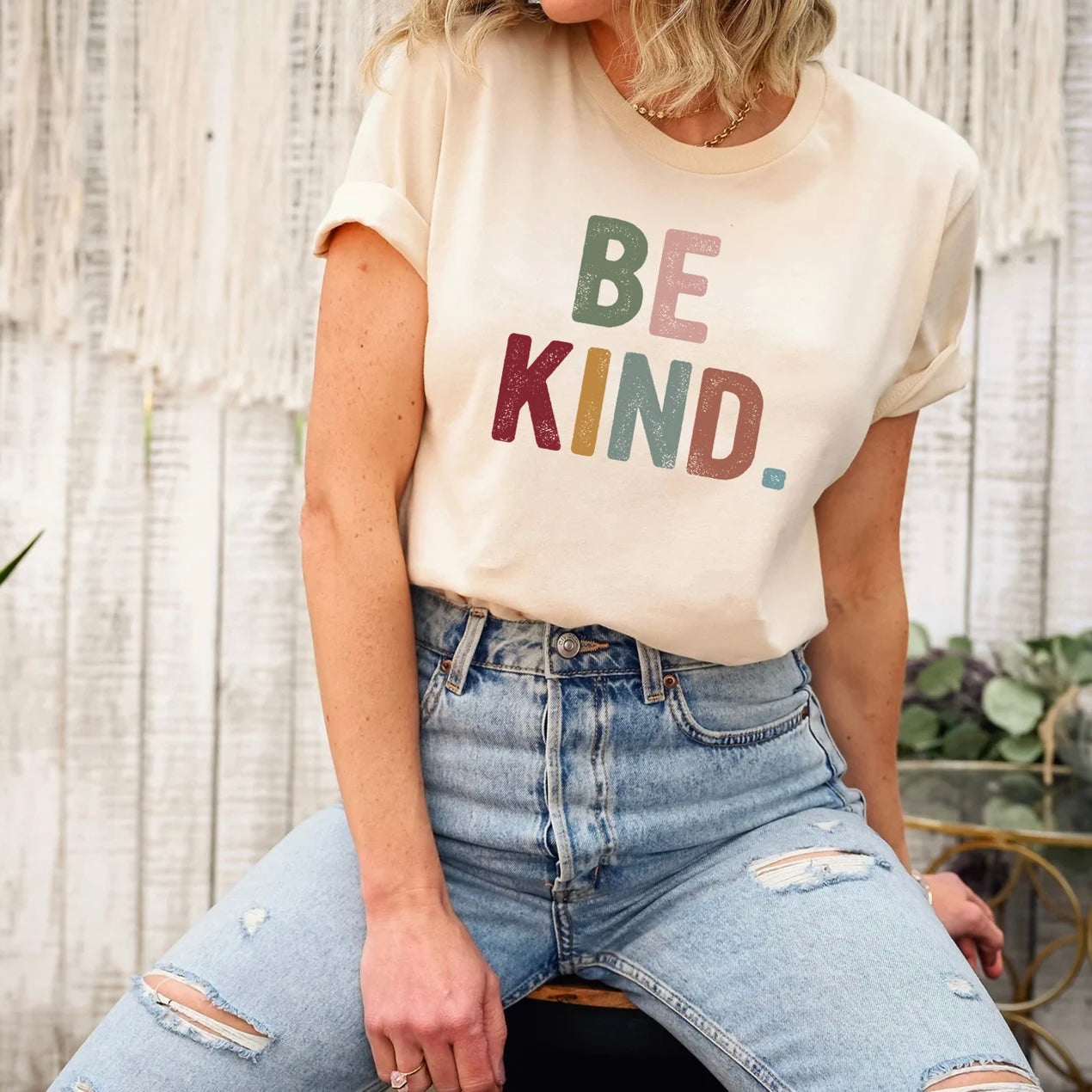 Close-up of beige "Be Kind" graphic tee.