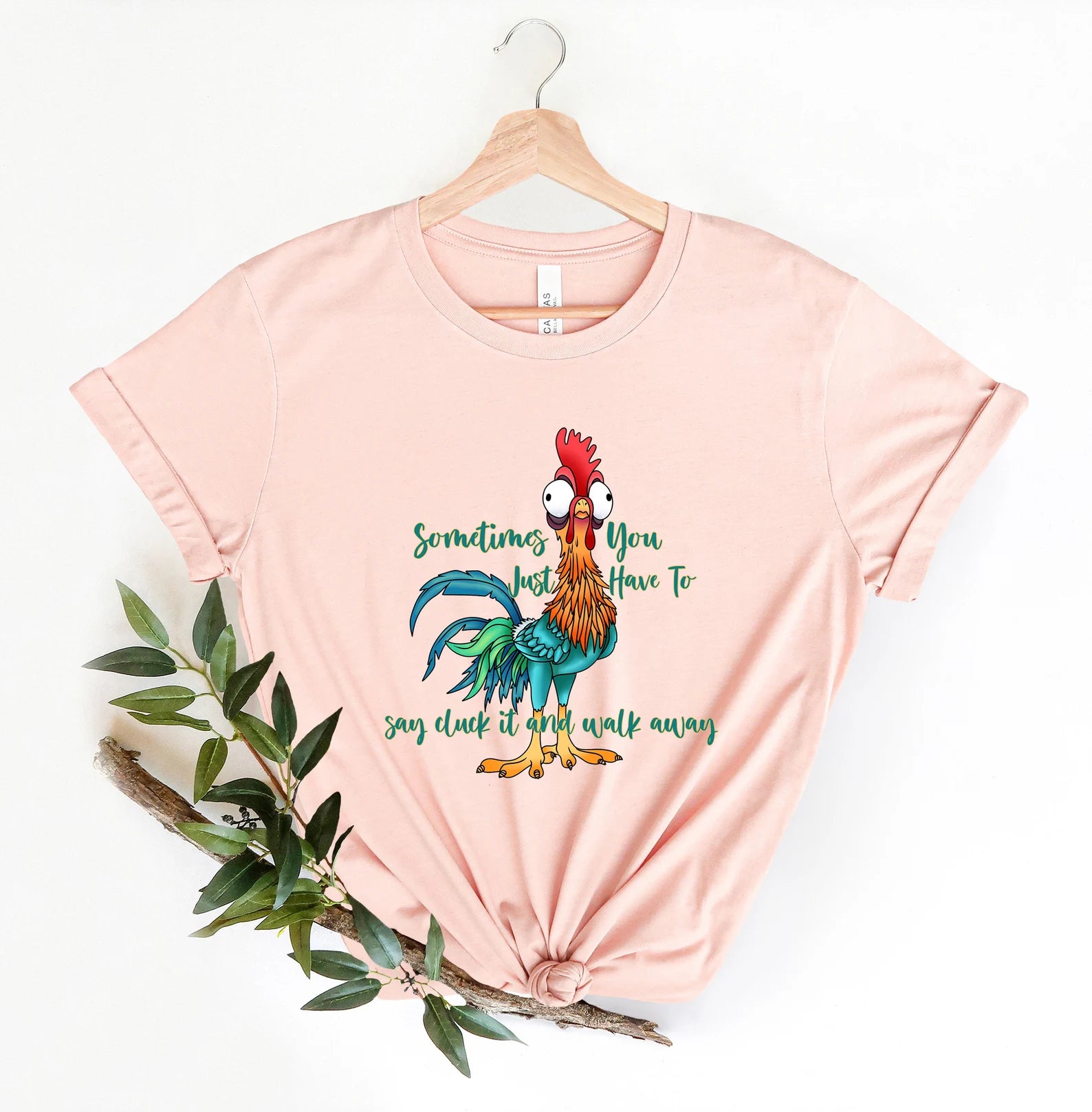 Soft pink shirt featuring a quirky chicken graphic and light-hearted phrase.