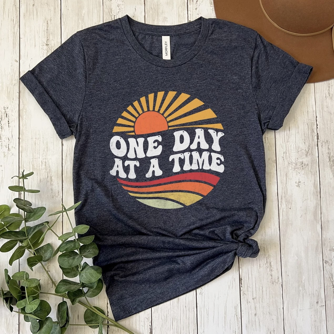 Close - up of 'One Day at a Time' sun graphic on a t - shirt