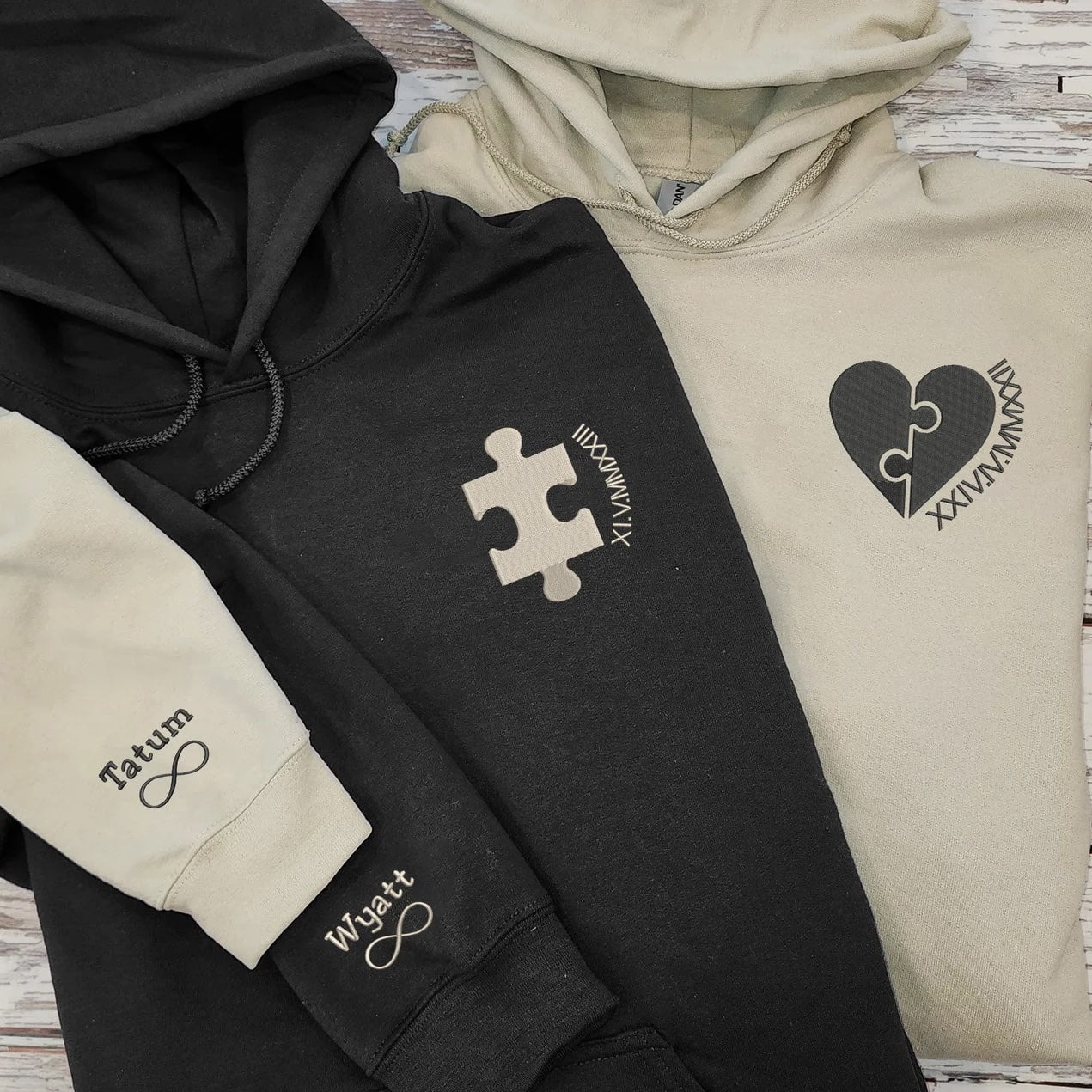 Matching couple hoodies featuring puzzle pieces, Roman numerals, and custom names.