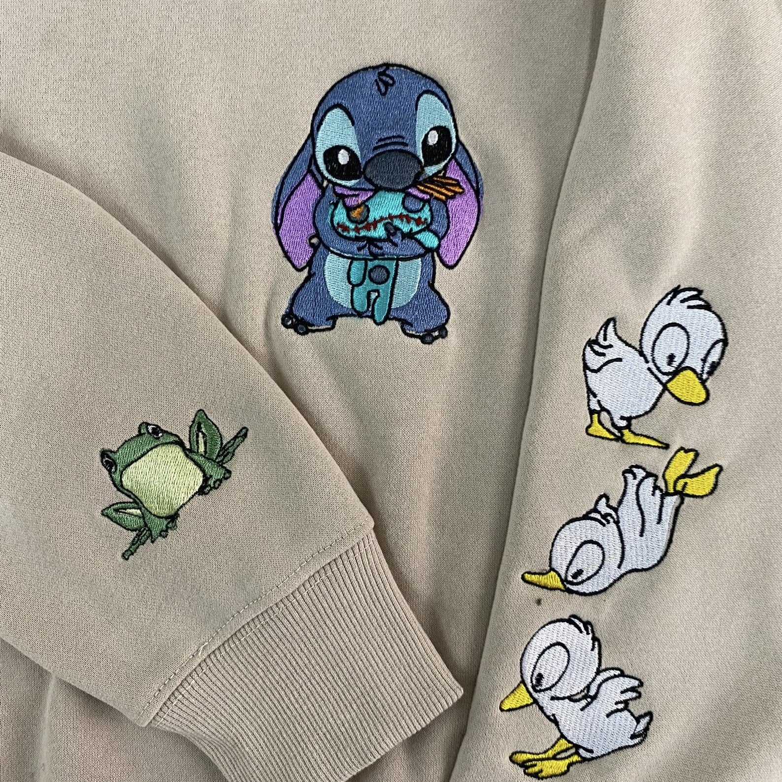 Embroidered Stitch sweatshirt with whimsical frog and duck designs on sleeves