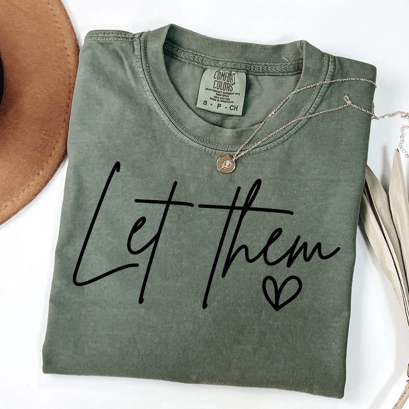 "Let Them" T-shirt in soft green with inspirational message.