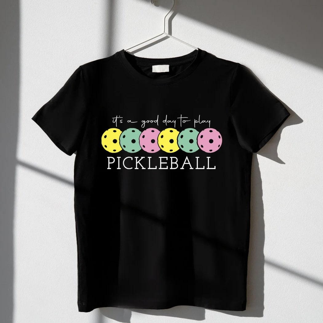 Black t - shirt with 'It's a Good Day to Play Pickleball' graphic hanging on a hanger