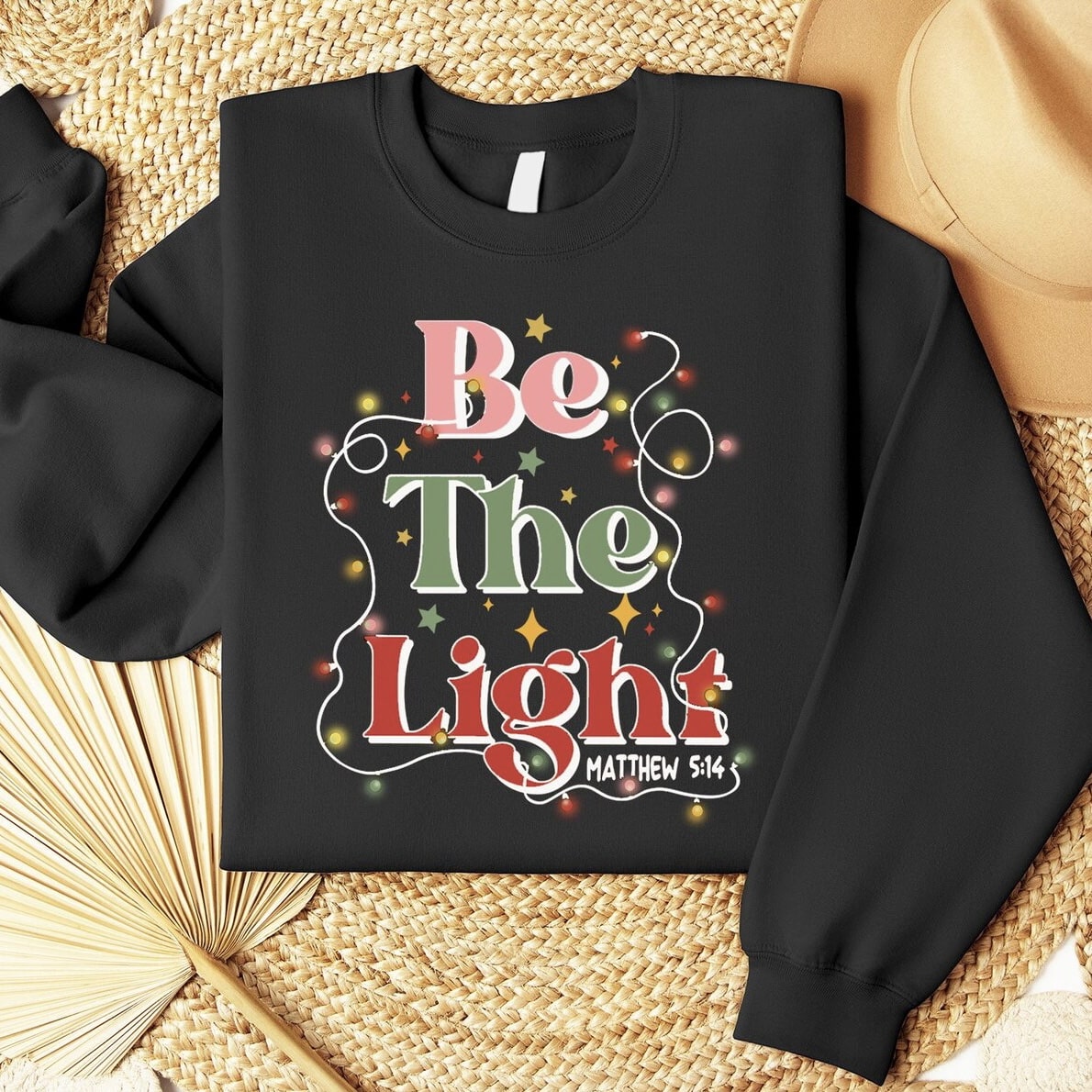 Be The Light holiday sweatshirt with colorful lights and stars for festive wear.