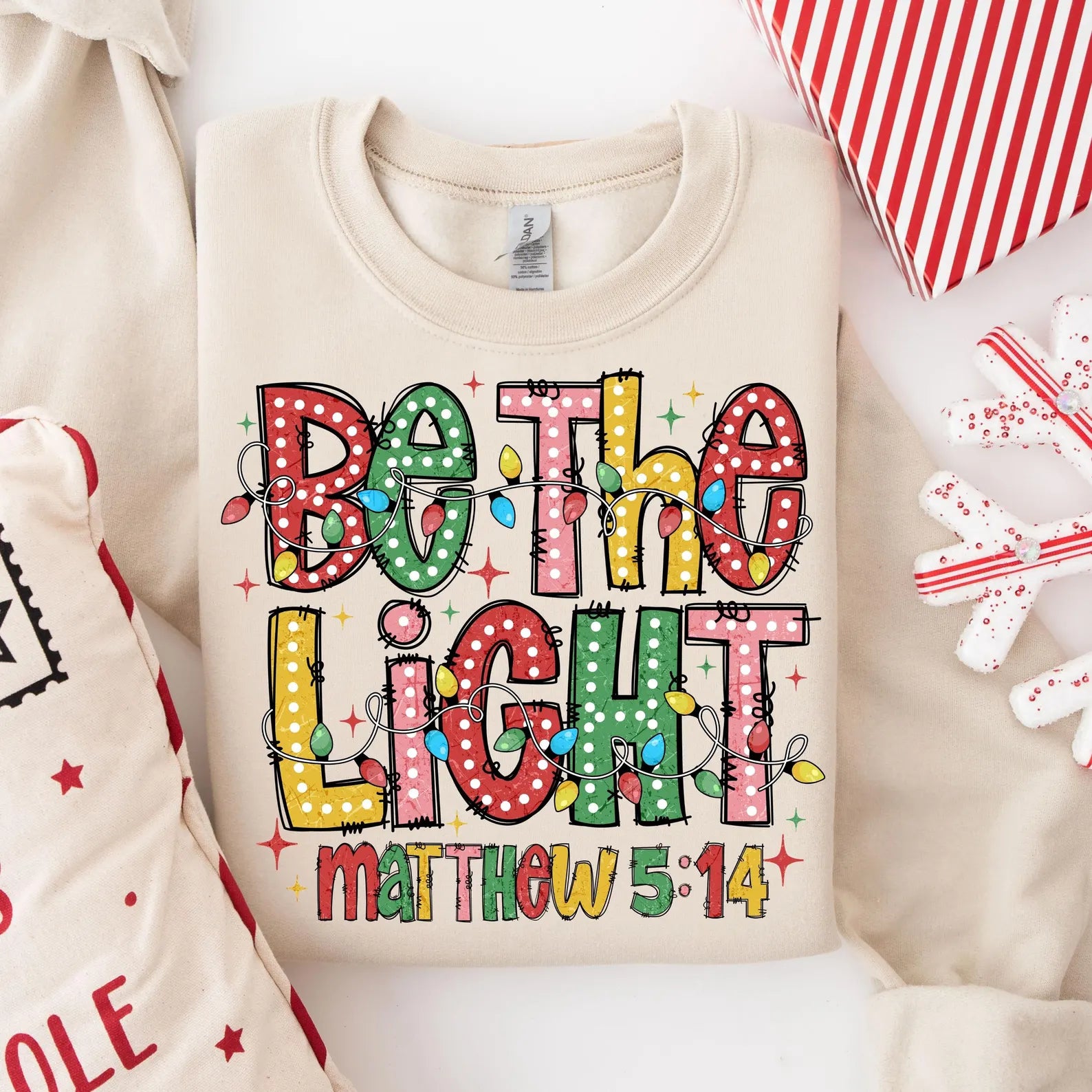 Comfortable holiday sweater with inspirational 'Be The Light' message and Christmas decor.