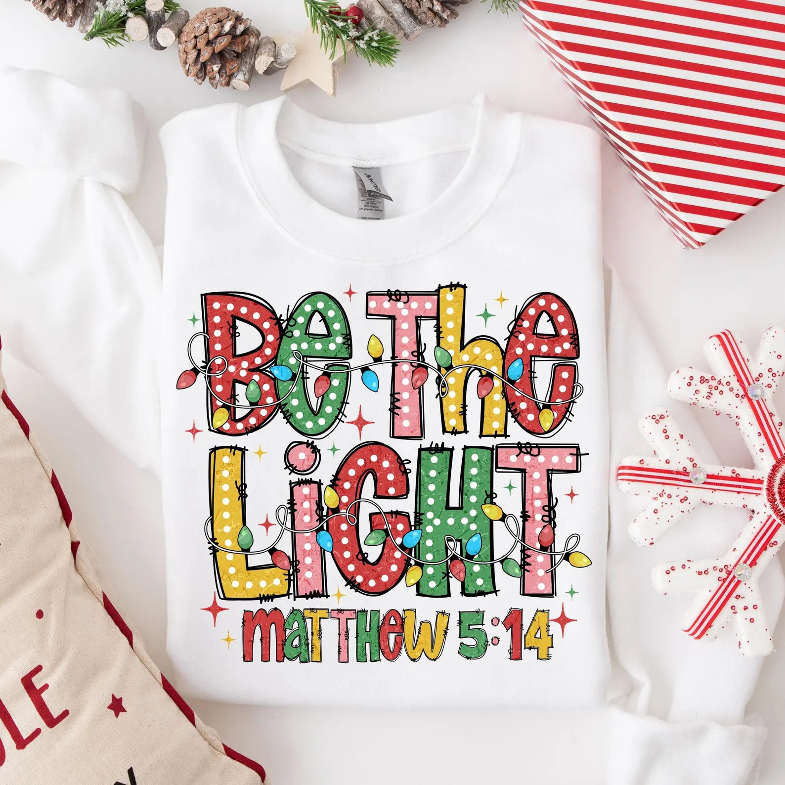 Christmas Bible verse sweatshirt featuring colorful festive design and Matthew 5:14.