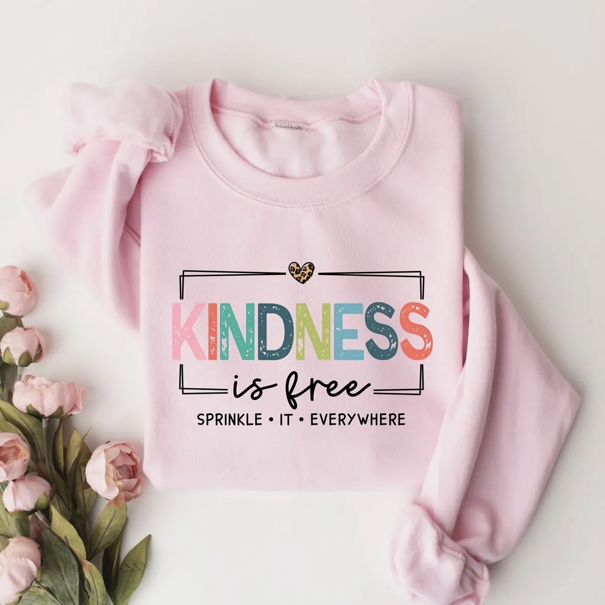 Close-up of "Kindness is Free" T-shirt with vibrant colors and playful font.