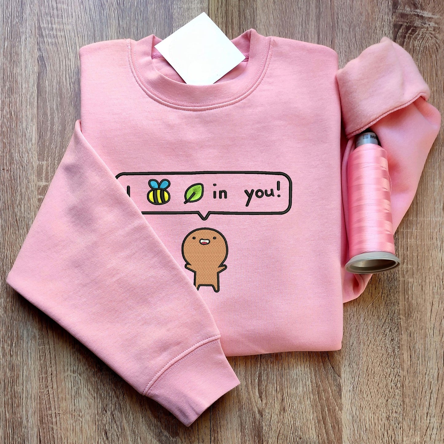 Custom embroidered graphic meme shirts showcasing a playful design on pink fabric, ideal for lovers of funny meme shirts.
