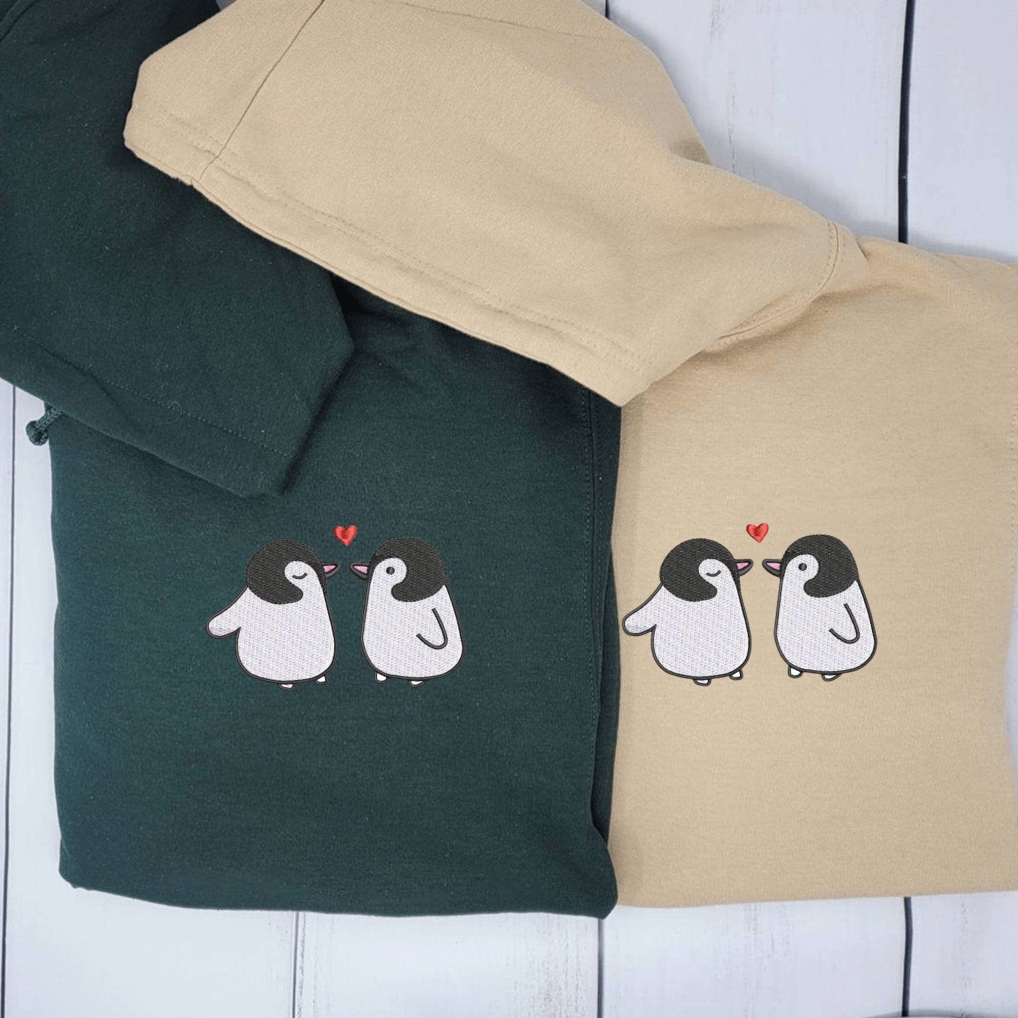 Matching penguin couple hoodies in green and beige, featuring penguins with hearts.

