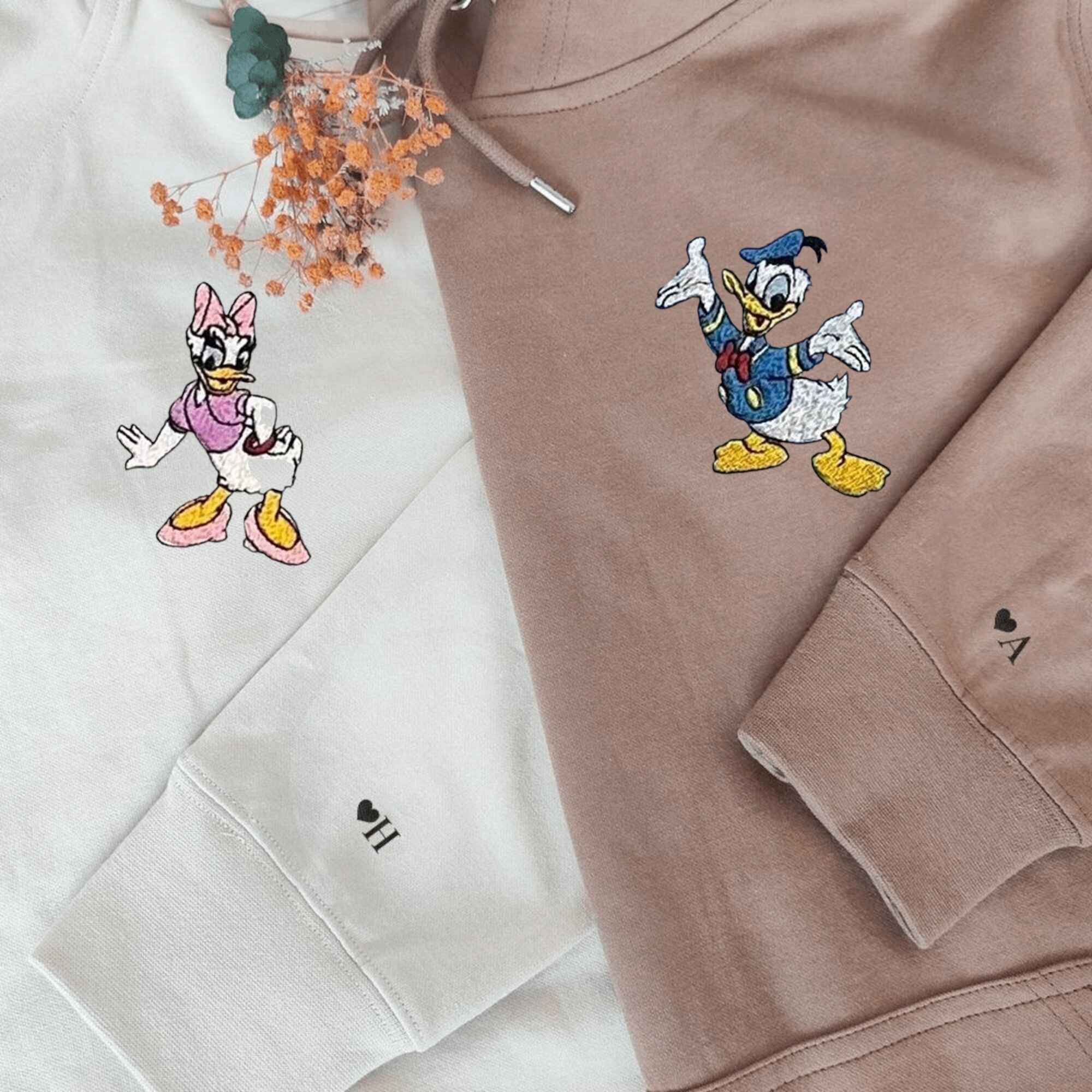 Matching Couple Hoodies featuring Donald and Daisy Duck designs with personalized details.
