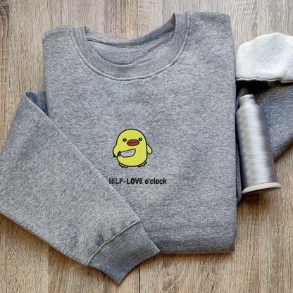 Custom embroidered graphic meme shirts showcasing a cute duck with a self-love message, perfect for fans of funny meme t-shirts.
