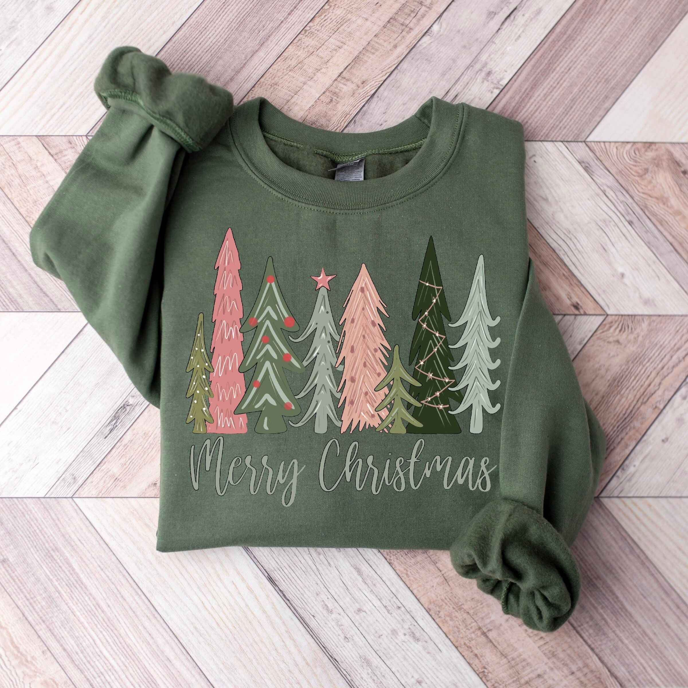 Festive holiday sweatshirt in green with "Merry Christmas" text and tree illustrations
