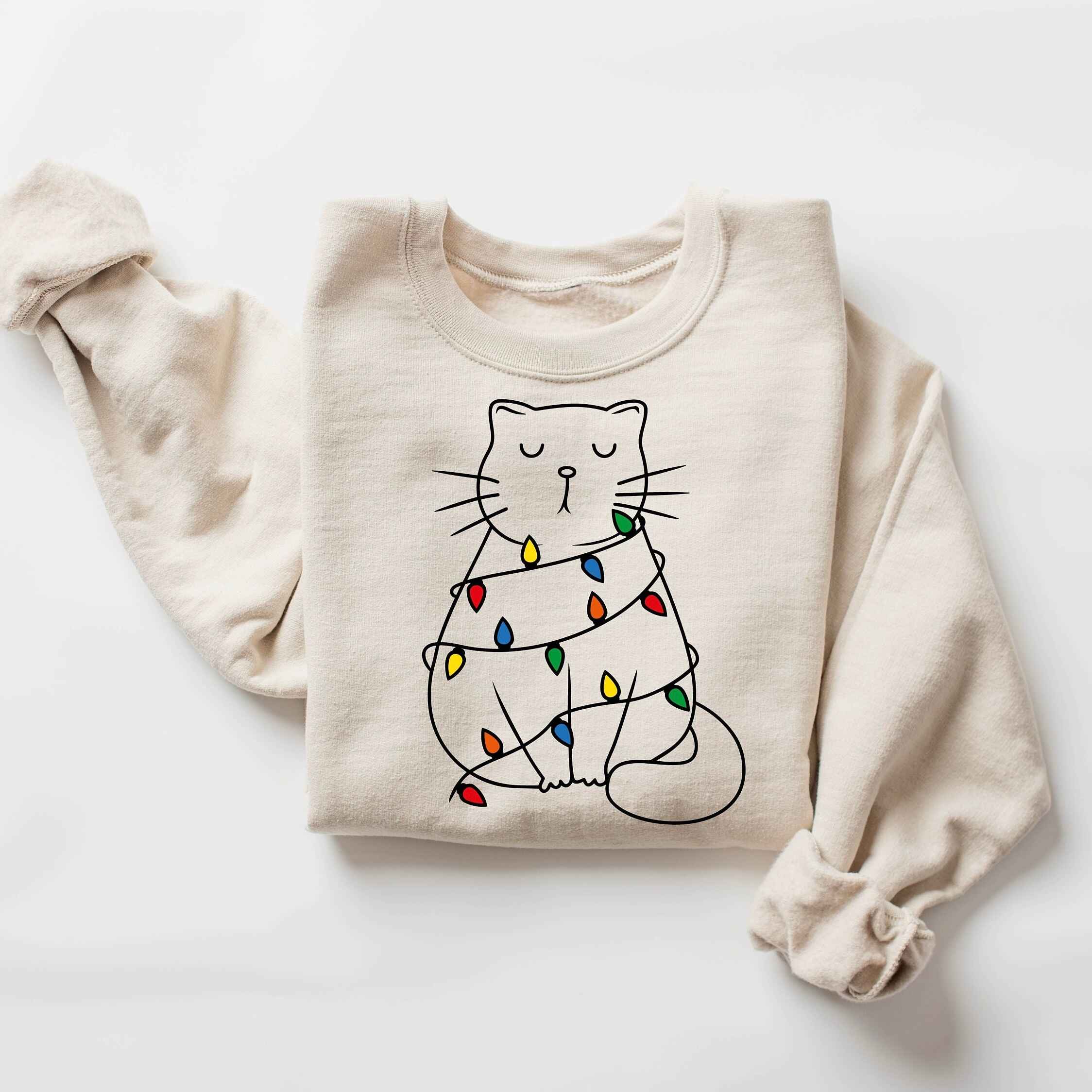 Christmas sweatshirt with a cat wrapped in holiday lights
