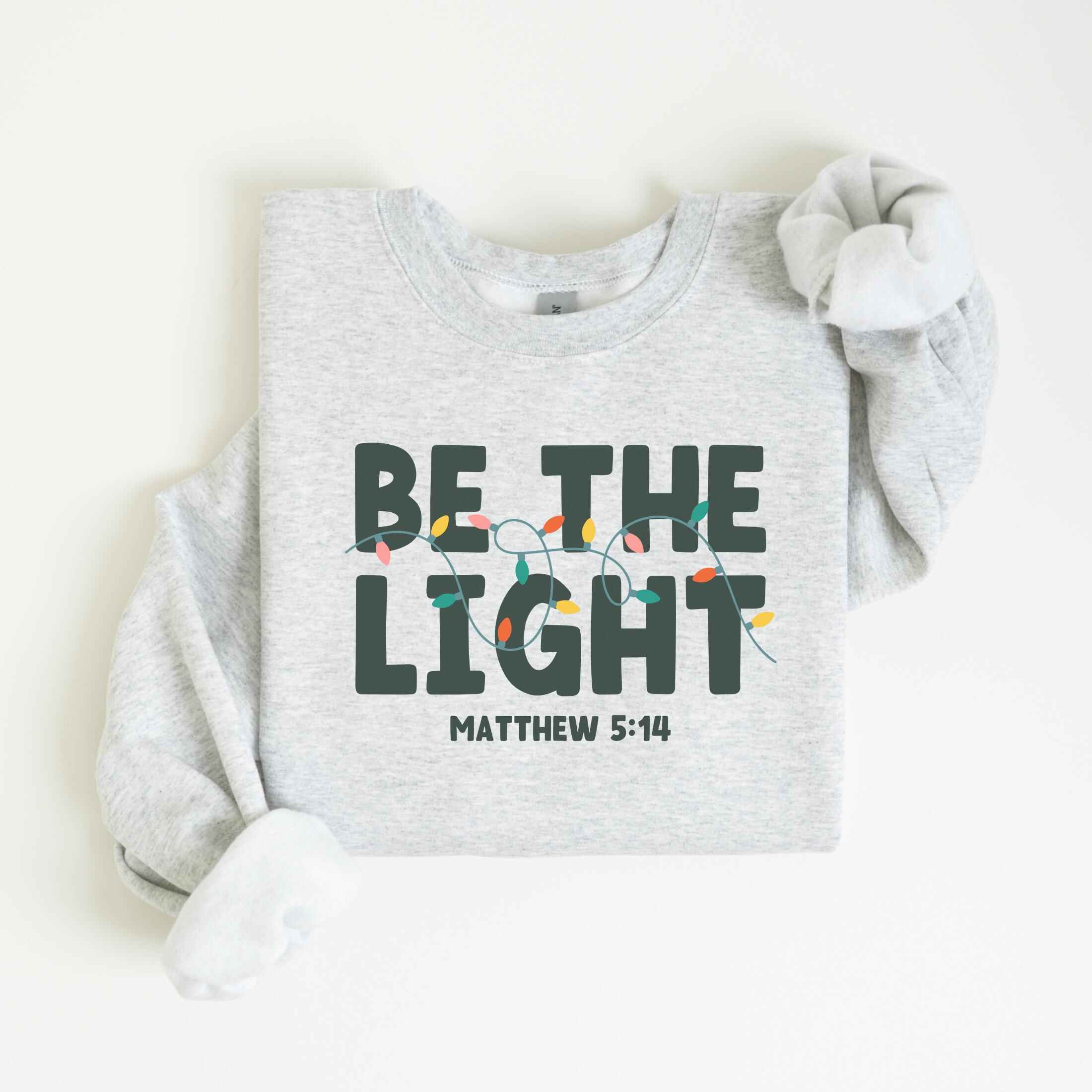 "Be the Light" Matthew 5:14 Christmas sweatshirt with festive lights
